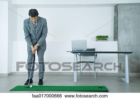 Businessman putting on artificial turf in office View Large Photo Image Stock Photograph - Businessman putting on artificial turf in office. Fotosearch