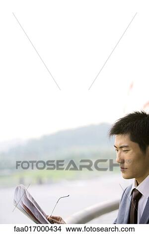 Picture - Businessman reading newspaper, side view. Fotosearch