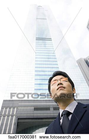 Businessman, skyscraper in background View Large Photo Image Stock Image - Businessman, skyscraper in background. Fotosearch