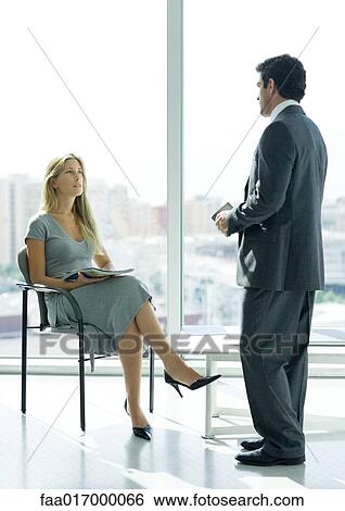 Businessman speaking to woman sitting in lobby View Large Photo Image Stock Photograph - Businessman speaking to woman sitting in lobby. Fotosearch