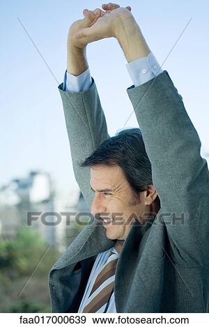 Businessman stretching arms over head View Large Photo Image Stock Photo - Businessman stretching arms over head. Fotosearch