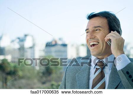 Businessman using cell phone and laughing, skyline in background View Large Photo Image Stock Photography - Businessman using cell phone and laughing, skyline in background. Fotosearch