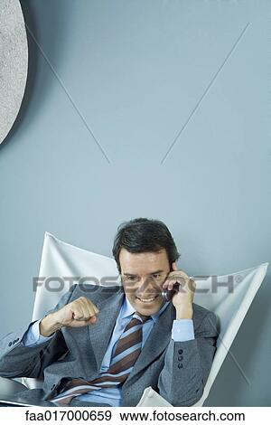 Businessman using cell phone, making fist, and smiling View Large Photo Image Stock Photo - Businessman using cell phone, making fist, and smiling. Fotosearch