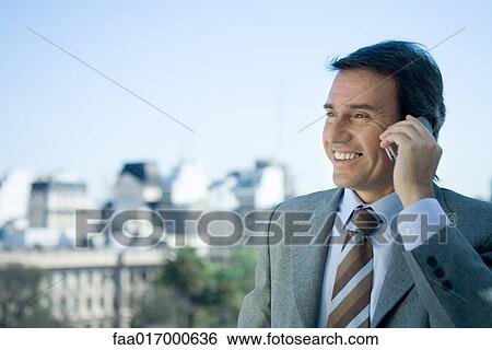 Businessman using cell phone, skyline in background View Large Photo Image Stock Photograph - Businessman using cell phone, skyline in background. Fotosearch