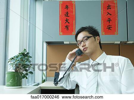Stock Photograph - Businessman using phone in office. Fotosearch