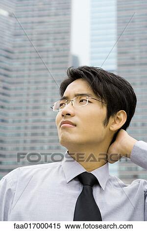 Businessman with hand on back of neck, looking up and frowning View Large Photo Image Stock Photography - Businessman with hand on back of neck, looking up and frowning. Fotosearch