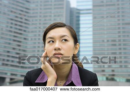 Businesswoman holding head and looking away, high rises in background View Large Photo Image Stock Photo - Businesswoman holding head and looking away, high rises in background. Fotosearch