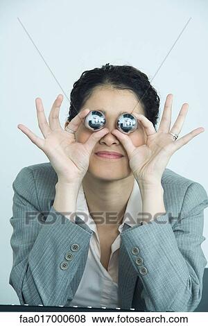Stock Photo - Businesswoman holding yinyang balls, in front of eyes. Fotosearch