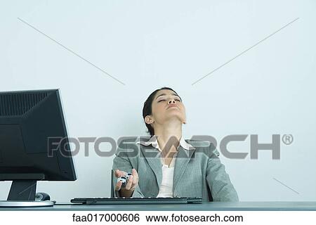 Businesswoman holding yinyang balls, sitting at desk, head back and eyes closed View Large Photo Image Stock Photograph - Businesswoman holding yinyang balls, sitting at desk, head back and eyes closed. Fotosearch