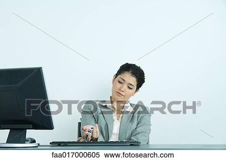 Stock Photography - Businesswoman holding yinyang balls, sitting at desk. Fotosearch