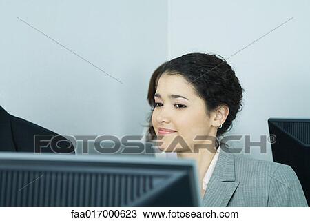 Businesswoman sitting at computer, smiling View Large Photo Image Stock Image - Businesswoman sitting at computer, smiling. Fotosearch