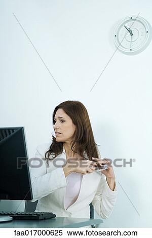 Businesswoman sitting at computer, brushing hair View Large Photo Image Stock Photography - Businesswoman sitting at computer, brushing hair. Fotosearch
