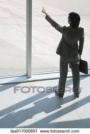 Businesswoman standing by window, pointing to distance, high angle view View Large Photo Image Stock Image - Businesswoman standing by window, pointing to distance, high angle view. Fotosearch