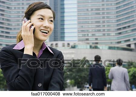 Stock Photo - Businesswoman using cell phone, smiling. Fotosearch