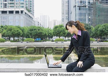 Businesswoman using laptop by water in office park View Large Photo Image Stock Image - Businesswoman using laptop by water in office park. Fotosearch