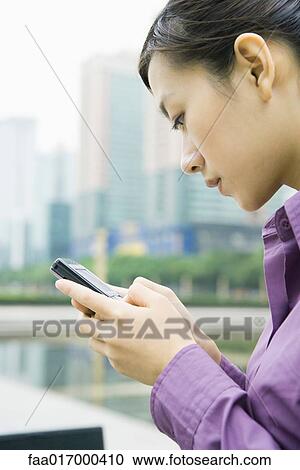 Businesswoman using messaging phone, close-up, side view View Large Photo Image Stock Image - Businesswoman using messaging phone, close-up, side view. Fotosearch