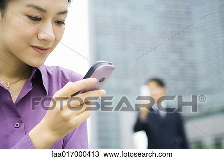 Stock Image - Businesswoman using messaging phone, close-up. Fotosearch