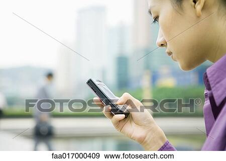 Businesswoman using messaging phone, close-up, side view View Large Photo Image Stock Photo - Businesswoman using messaging phone, close-up, side view. Fotosearch