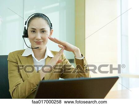 Businesswoman wearing headset and using laptop, making time out gesture View Large Photo Image Stock Photo - Businesswoman wearing headset and using laptop, making time out gesture. Fotosearch