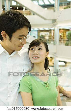 Stock Image - Couple in shopping mall, looking at each other. Fotosearch