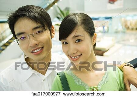 Stock Photo - Couple in shopping mall, smiling at camera, portrait. Fotosearch