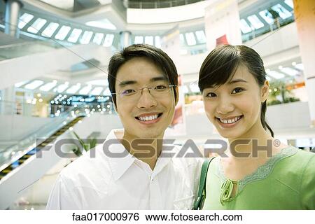 Stock Photograph - Couple in shopping mall, smiling at camera, portrait. Fotosearch