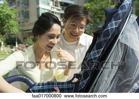 Couple looking down into baby carriage View Large Photo Image Stock Image - Couple looking down into baby carriage. Fotosearch