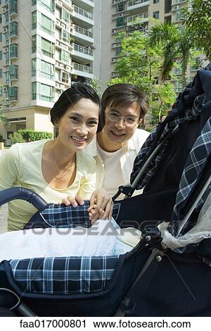 Stock Image - Couple looking down into baby carriage. Fotosearch
