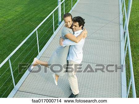 Picture - Couple on walkway, man spinning woman around in his arms. Fotosearch