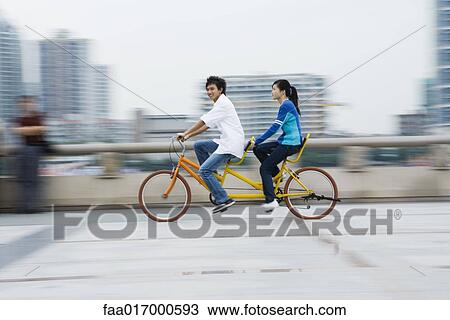Stock Image - Couple riding tandem bicycle. Fotosearch