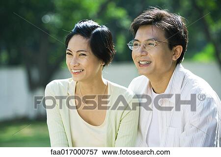 Stock Photo - Couple smiling, looking out of frame, portrait. Fotosearch