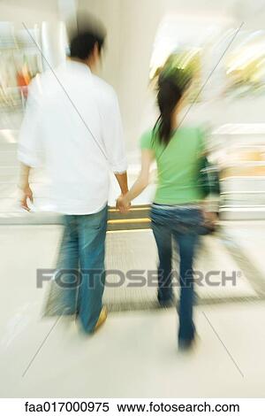 Couple walking in shopping mall, rear view, blurred motion View Large Photo Image Stock Photography - Couple walking in shopping mall, rear view, blurred motion. Fotosearch