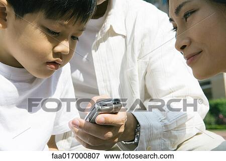Stock Photo - Family, boy looking at cell phone. Fotosearch