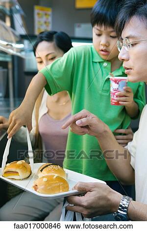 Family eating fast food, boy picking up bun from tray View Large Photo Image Stock Photograph - Family eating fast food, boy picking up bun from tray. Fotosearch