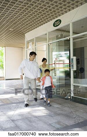 Stock Image - Family exiting apartment building lobby. Fotosearch