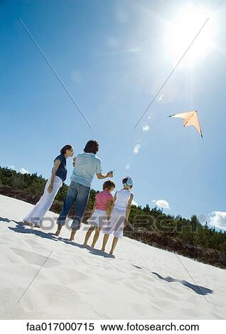 Stock Photography - Family flying kite on beach. Fotosearch