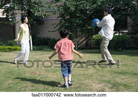 Stock Image - Family playing ball on grass, full length. Fotosearch