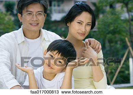 Stock Image - Family, smiling at camera, boy shrugging. Fotosearch