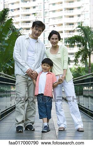 Stock Image - Family standing on walkway, portrait. Fotosearch