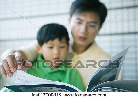 Father and son looking at book together View Large Photo Image Stock Photograph - Father and son looking at book together. Fotosearch