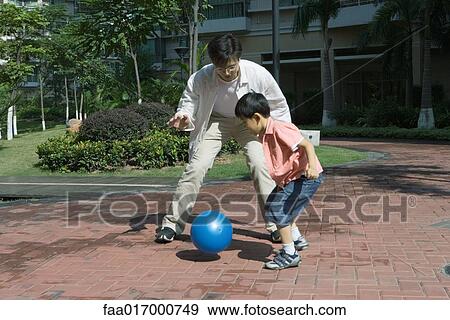 Stock Photo - Father and son playing ball in courtyard. Fotosearch