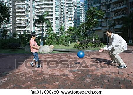 Stock Image - Father and son playing ball in apartment complex. Fotosearch