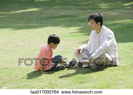 Father and son sitting on grass View Large Photo Image Picture - Father and son sitting on grass. Fotosearch