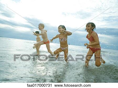 Stock Image - Four children racing in shallow water. Fotosearch