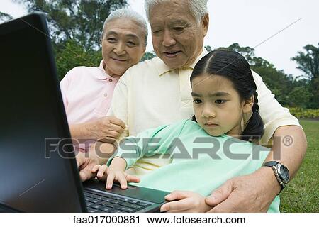 Stock Image - Girl and grandparents using laptop. Fotosearch
