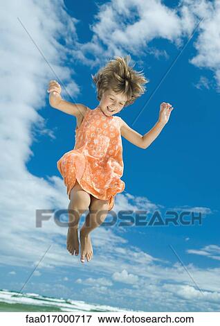 Girl jumping in mid air, sky in background View Large Photo Image Stock Photo - Girl jumping in mid air, sky in background. Fotosearch