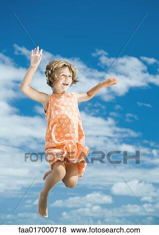 Stock Photo - Girl jumping in mid air, sky in background. Fotosearch