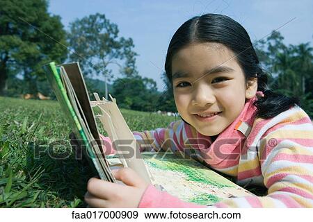 Stock Photo - Girl lying in grass with pop-up book. Fotosearch