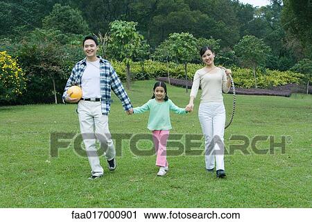 Girl walking hand in hand with parents, full length View Large Photo Image Stock Image - Girl walking hand in hand with parents, full length. Fotosearch