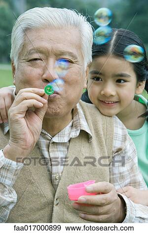 Stock Photo - Girl with grandfather blowing bubbles. Fotosearch